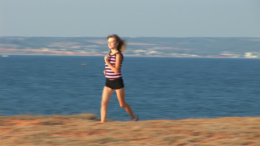 A young woman jogs along the seaside. 