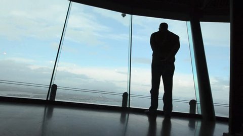 AUCKLAND - OCT 10 2013: Silhouette of a man looking out the window of Sky Tower.Auckland has been rated one of the world's top 10 cities to visit by Lonely Planet on October 2013.