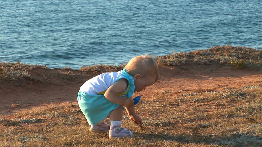 A young child plays along the seaside.