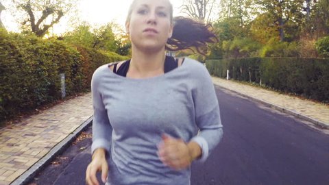 Young fitness woman having an exercise run in a residential area. Caucasian model in the 20s. Close shot of upper body with camera following. 