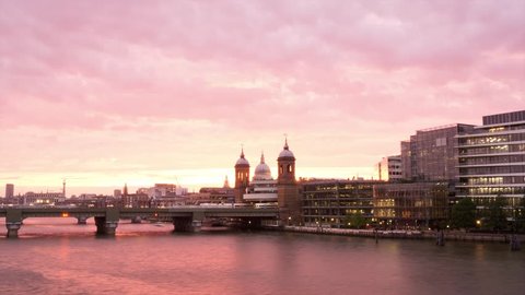 Sunset over the City of London. Thames River and office buildings, with Blackfriar's Bridge in the center. A passenger boat passes by.