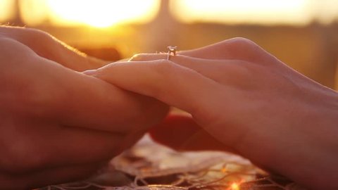 Proposal Putting on Engagement Ring at sunset close up hands