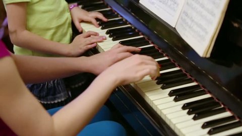 Little girl stands near mother which plays on piano with notes