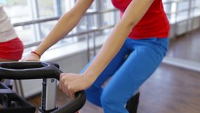 Close-up of healthy women spinning the pedals of exercise bicycles