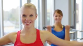 Close-up of cheerful girls doing dumbbell exercises for biceps