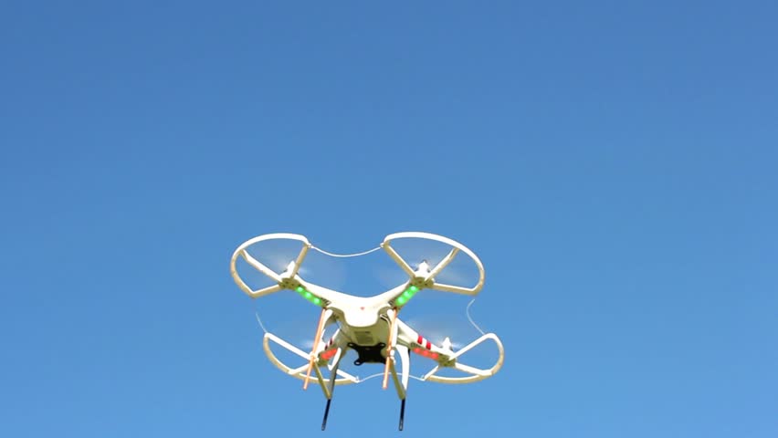 Quadrocopter flying overhead against a blue sky