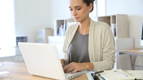 Attractive woman working in office on laptop