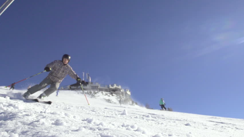 Slow Motion Of Skiers Carving Down Steep Slope. Focus On Snow Spraying Against