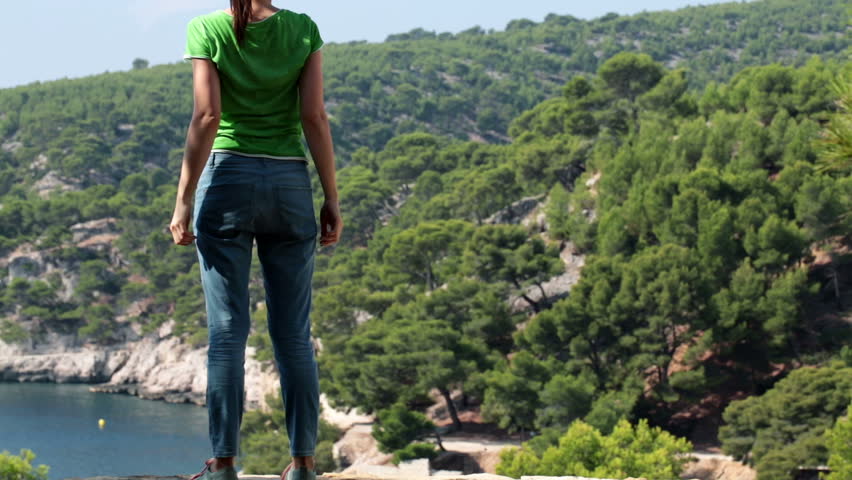 Successful woman raising hands to sky in beautiful nature scenery
