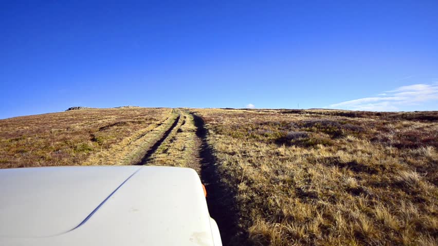 Off-road driving through a mountain horizon plateau at high altitude peak uphill