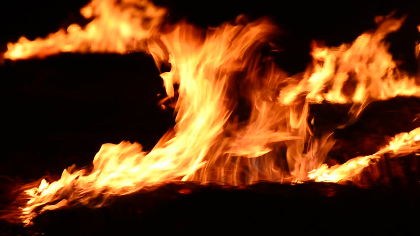 burning fire flames at dark, panning shoot. Could be used as overlay alpha with