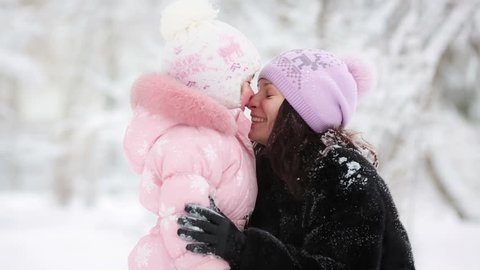 Happy woman and child playing with snow in winter park