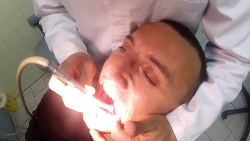 man having his teeth fixed at the dentist's. Drill preparation, caries cleanup