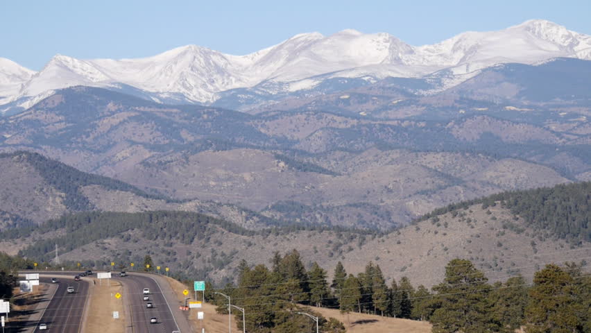 Interstate highway, pan up to the scenic backdrop of the continental divide, in