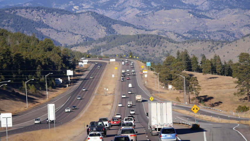Interstate highway, pan up to the scenic backdrop of the continental divide, in