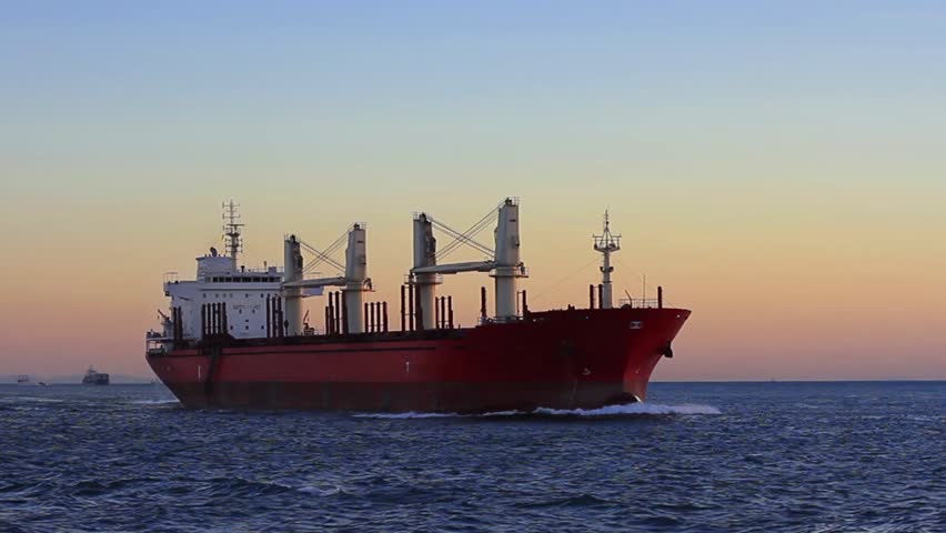 Cargo ship sailing from open sea. A bulk carrier ship with deck cranes on the