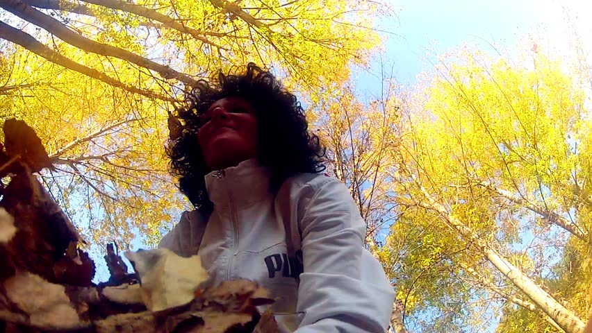 Woman throws fall leaves into air - Stock Video