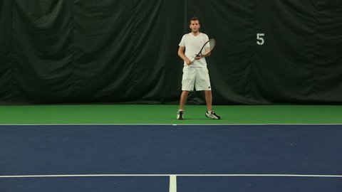 Young man practicing his Tennis skills at an indoor court 