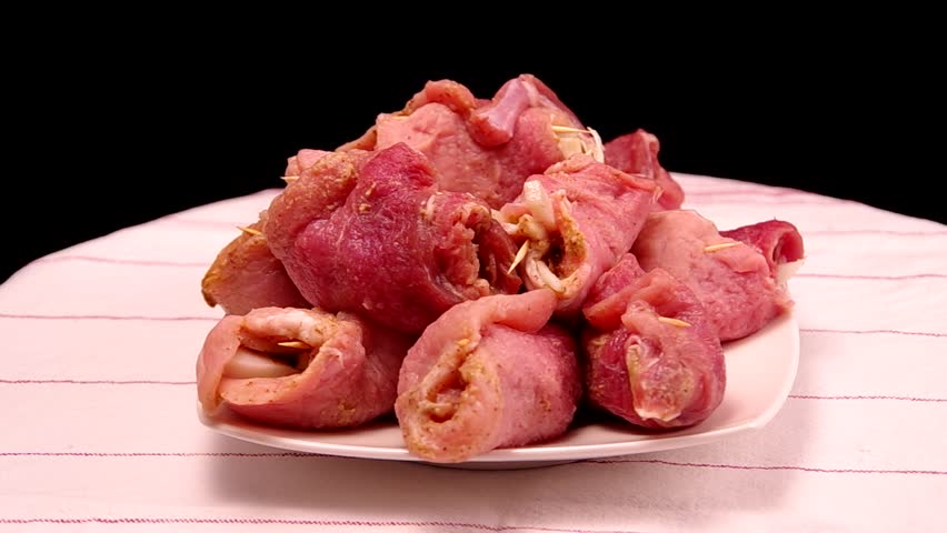 Raw stuffed pork slices are rotating on the table.
