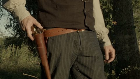A cowboy from the American wild west era fires his black powder pistol