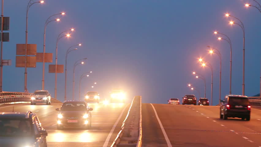 Highway traffic, cars drive with lights on, evening dusk road