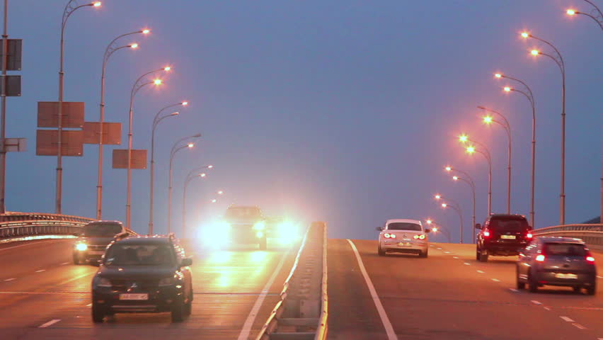 Dense evening traffic, cars drive lights dusk city highway road