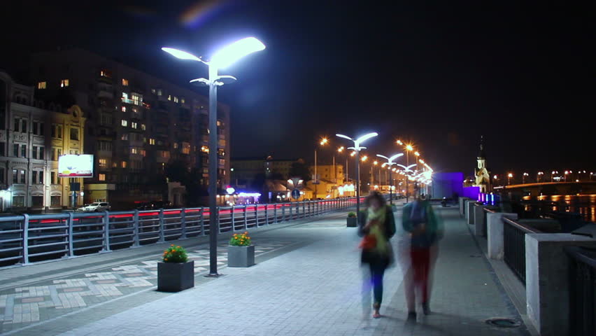 Night city quay, people walking, cars driving, street lights on