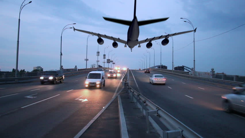 Airplane landing above city highway, transportation traffic dusk
