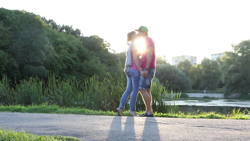 Young couple kissing at sunset, romantic love, sunshine kiss