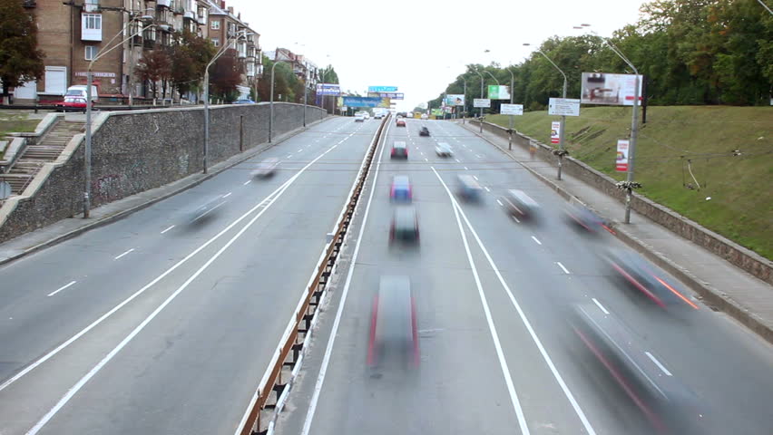Small city street time lapse, cars drive both ways, bridge