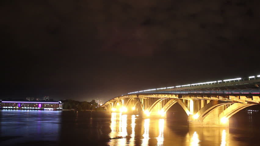 River bridge at night, cars drive water flows, clouds time-lapse