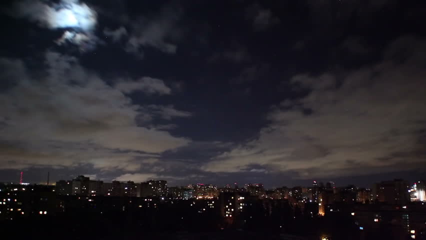 Night city timelapse, houses buildings shine lights, clouds move