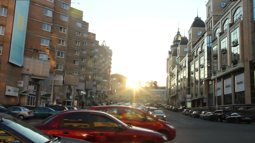 Cars on street traffic jam city, dusk sunlight, high buildings