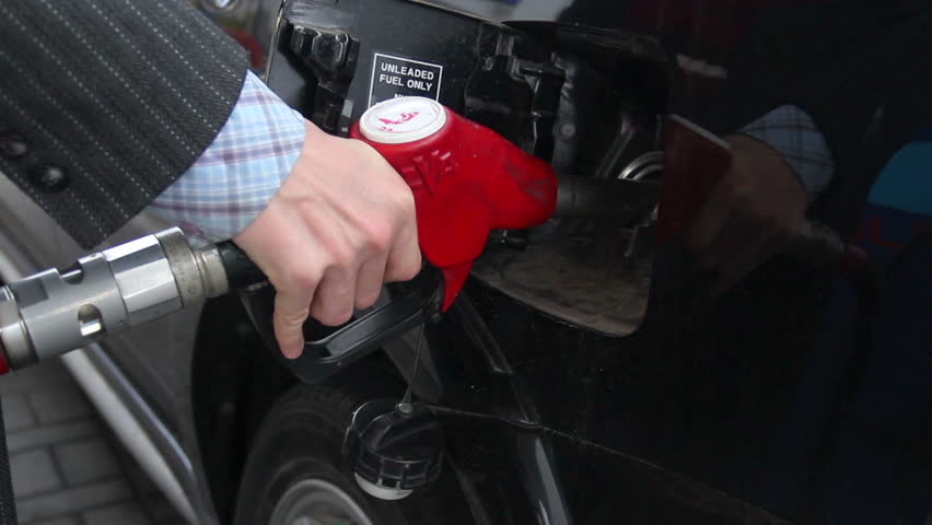 Businessman pulls out gasoline pistol fueling car petrol station