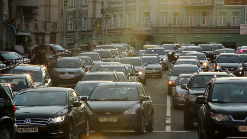 City cars vehicles lined traffic jam, dusk sun rays, movement