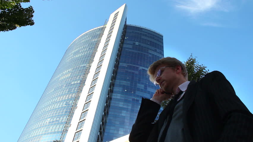 Stock broker businessman talks business phone, office building