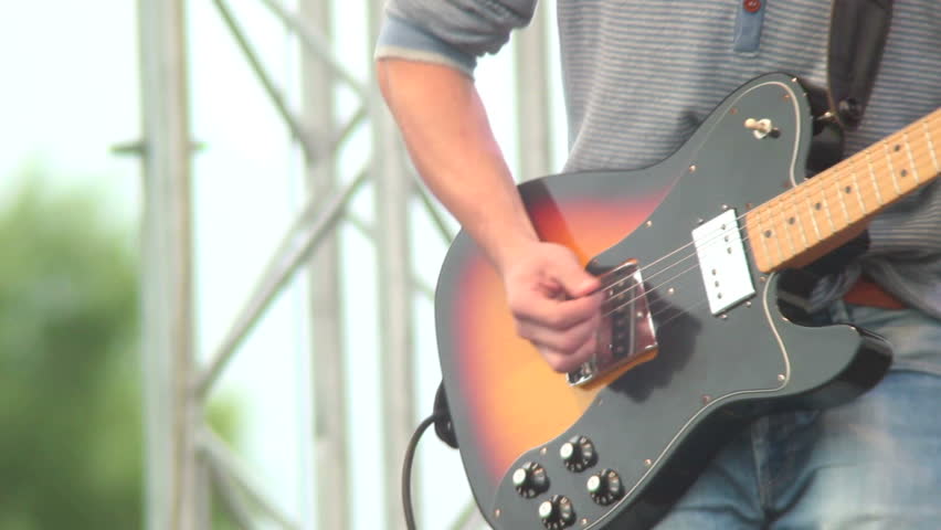 Musician with guitar playing on stage, day concert, rock