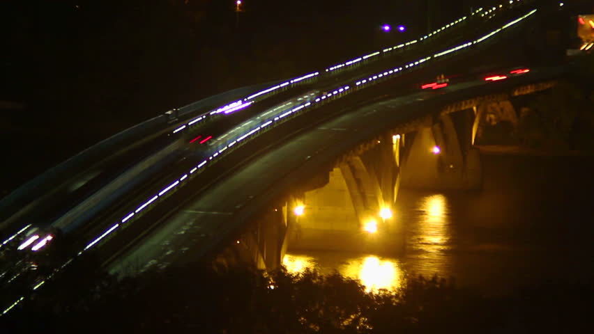 Night river bridge, cars leave traces yellow red light timelapse