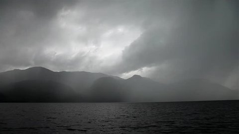 Stormy sky above the black mountain lake.