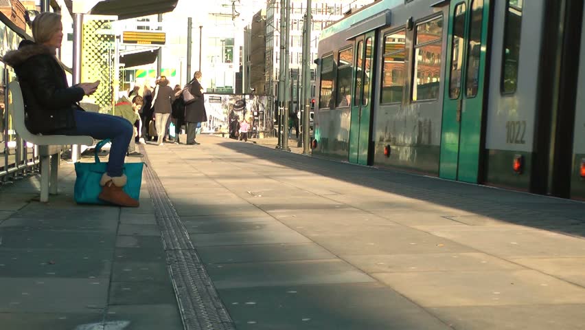 MANCHESTER CIRCA 2013: People waiting as a tram drives to a stop - Manchester