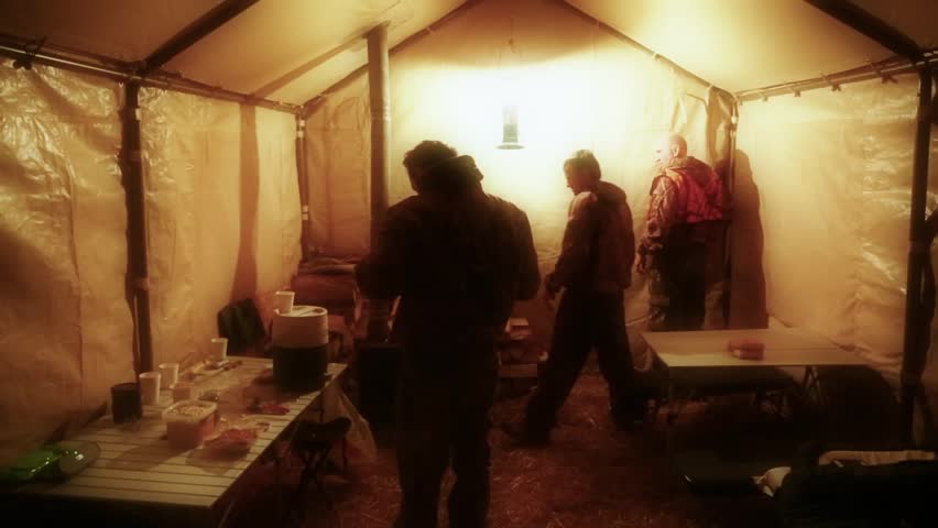 Hunters camping in a wall tent with a wood burning stove