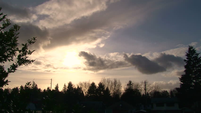 Time lapse during sunset with rain clouds building around sun.