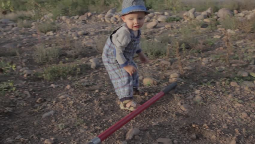 A little boy trying to use a shovel 
