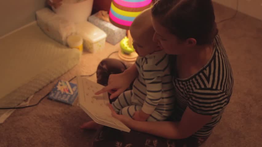 A baby boy and his mother reading a bedtime story before going to sleep