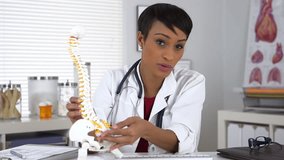 Black woman doctor explaining spine model