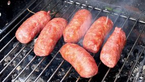 A clip presenting some sausages while are cooking and roasting on a barbecue grill