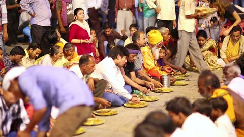 VARANASI, INDIA - MAY 2013: poor indian people eating free food at street at night