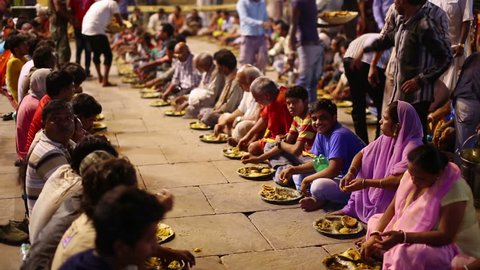 VARANASI, INDIA - MAY 2013: poor indian people eating free food at street at night