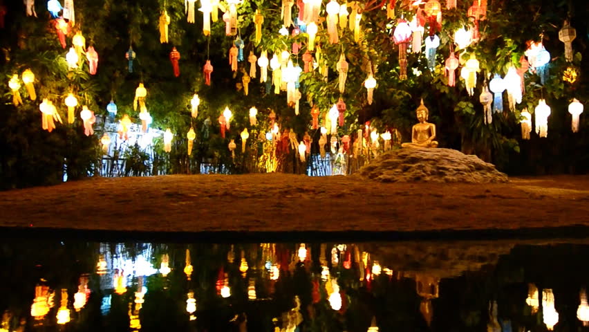 gold buddha image under beautiful lantern tree and reflection of pond