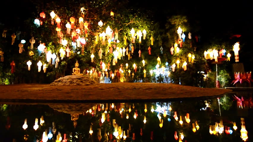 gold buddha image under beautiful lantern tree and reflection of pond
